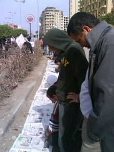 Egyptian protesters sharing newspapers